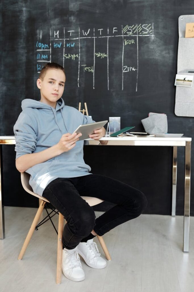 Teenager in casual outfit studying online at home using a tablet.